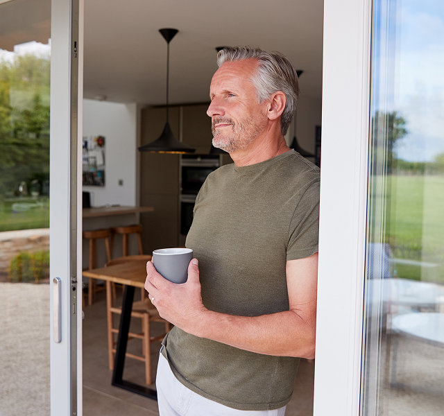 man looking out with cup in hand
